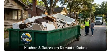 Green EverHaul dumpster filled with kitchen and bathroom remodel debris including cabinets, tile, and tubs on a Lakeland, FL street